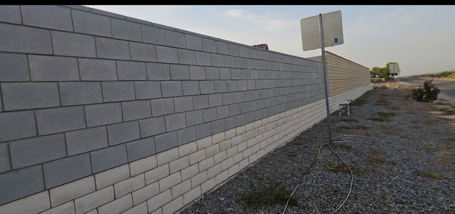 Long block wall painted in two tones of gray with a straight color line