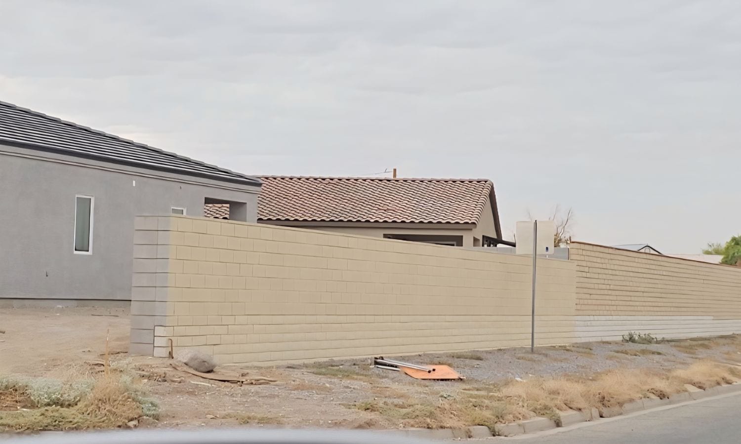 Tan painted block wall in front of a finished home